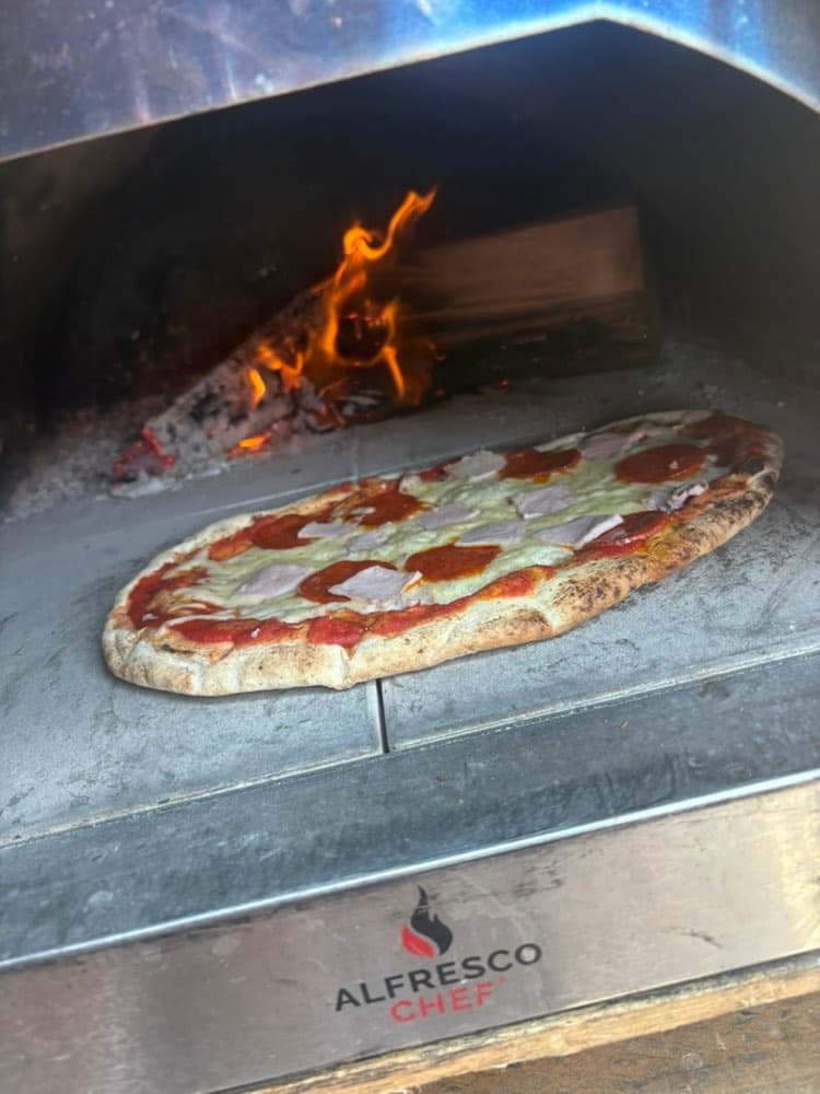 Wood-fired Neapolitan pizza cooking in our 500°C oven at a Cotswolds event